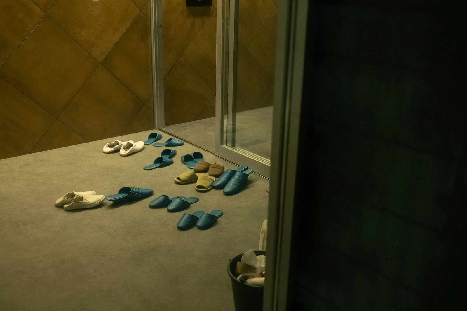 Slippers arranged on the floor of an entrance lit in warm light.