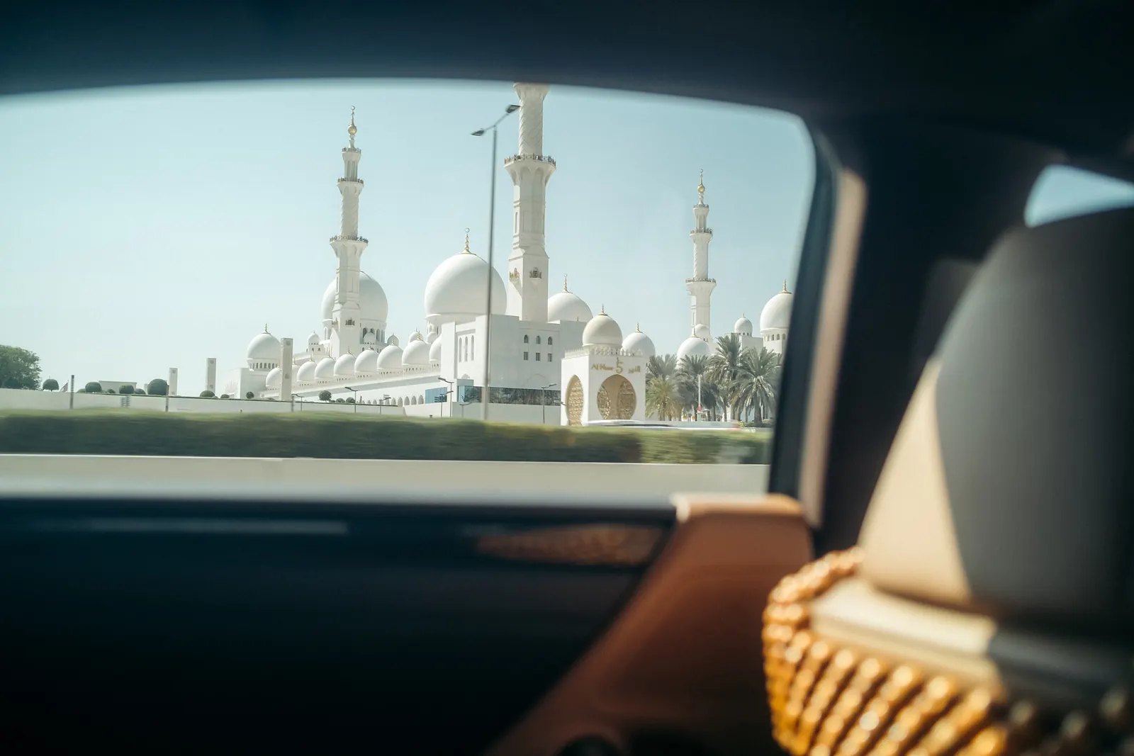 Sheikh Zayed Grand Mosque's minarets and domes seen through a taxi's rear window.
